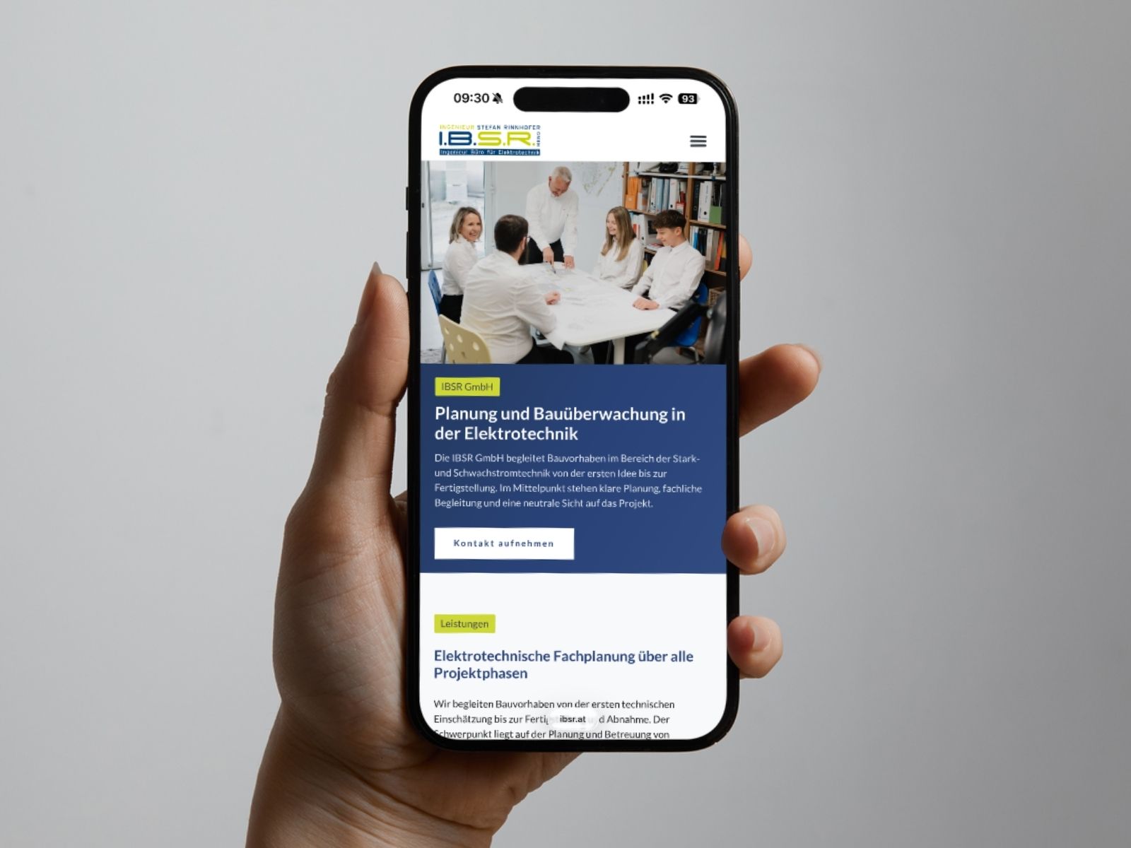 Hand hält Handy mit der IBSR-Website und einem Teamfoto des Büros